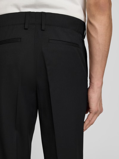 Männermodel trägt Slim Fit Anzughose mit Woll-Anteil von Filippa K, Schwarz, Elastischer-Material-Mix, Bundfalten, Nahaufnahme Rückansicht.
