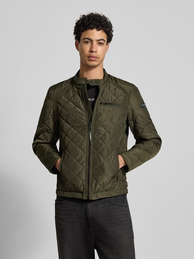 Männermodel trägt Regular Fit Jacke in Stepp-Optik von Replay in Olivgrün mit Stehkragen, Reißverschlüssen und Logo-Applikation, Ganzkörperansicht von vorne.