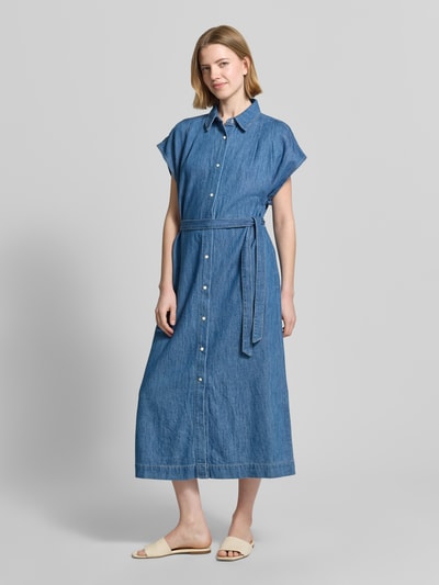 Frauenmodel trägt Regular Fit Jeanskleid aus reiner Baumwolle von s.Oliver RED LABEL in mittelblauem Denim mit Kontrastnähten, Bindegürtel und kurzen Ärmeln, Midi-Länge, hochgeschlossen, Druckknöpfe, Ganzkörperansicht von vorne.