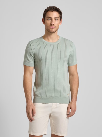 Männermodel trägt Strickshirt aus Viskose-Baumwoll-Mix Modell 'LINDON' von Guess, Slim-Fit, Rundhalsausschnitt, hellgrün, Ganzkörperansicht von vorne.