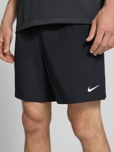 Mannenmodel draagt Shorts met Logo-Print en Steekzakken van NIKE TRAINING, rechte fit, elastische tailleband met koord, steekzakken, logo-opdruk, kleur zwart, detailopname bovenbenen, context: taillewijdte maat M 41 cm, binnenbeenlengte maat M 19 cm.
