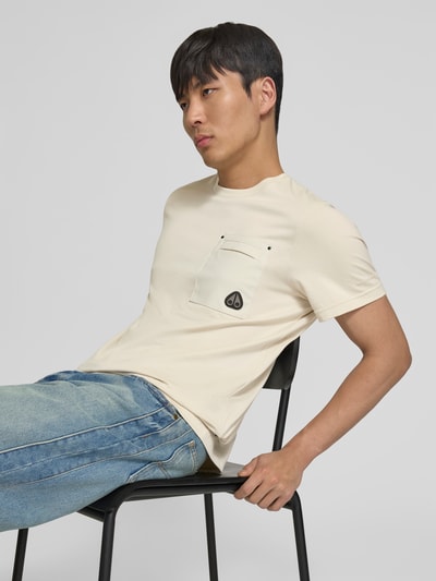 Männermodel trägt Regular Fit T-Shirt mit Brusttasche von Moose Knuckles in Beige, reine Baumwolle, Rundhalsausschnitt, Nahaufnahme Oberkörper.