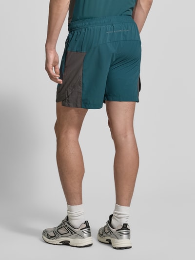Männermodel trägt Shorts mit Reißverschlusstaschen Modell 'HALO DIVISION' von HALO in Blau-Grau, Regular Fit, elastischer Bund, Ganzkörperansicht Rückansicht. Bundweite bei Größe M: 40 cm, Innenbeinlänge bei Größe M: 10 cm.