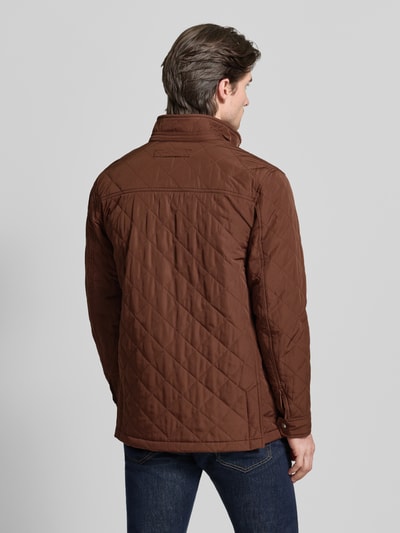 Męski model nosi kurtkę pikowaną Regular Fit Steppjacke mit Logo-Stitching model 'Windcheater' od Gant w brązowym kolorze, z efektem pikowania, stójką, wpuszczanymi i patkowymi kieszeniami, długość tyłu 76 cm, szerokość ramion 49 cm, szerokość klatki piersiowej 56 cm, długość rękawów 66 cm. Ganzkörperansicht Rückansicht.