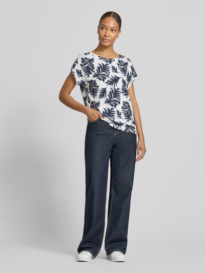Frauenmodel trägt Regular Fit T-Shirt aus Viskose-Mix von Tom Tailor mit Optik:Allover-Muster, floralem Muster, U-Boot-Ausschnitt, Materialverarbeitung: Stretch, Ganzkörperansicht von vorne.