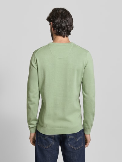 Męski model nosi Regular Fit Pullover aus reiner Baumwolle od s.Oliver RED LABEL, melanżowa zieleń, krój regular fit, okrągły dekolt, długi rękaw, drobny splot, bawełna, widoczne label stitching, wygodne ściągacze, tył produktu, zdjęcie całej sylwetki z tyłu.