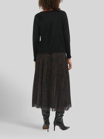 Frauenmodel trägt schwarzen Relaxed Fit Pullover aus Viskose-Mix von s.Oliver BLACK LABEL, kombiniert mit dunkel gemustertem Plisseerock, Ganzkörperansicht Rückansicht. Damen Pullover von s.Oliver BLACK LABEL.