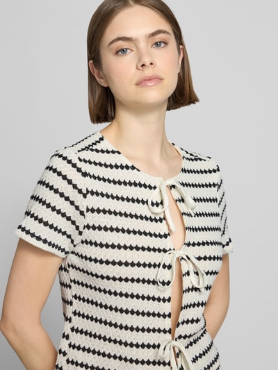 Frauenmodel trägt Regular Fit Strickshirt mit Baumwoll-Anteil Modell 'EVA' von Only, Optik:Allover-Muster, Rundhals, Kurzarm, Bindeverschluss, Nahaufnahme Oberkörper.