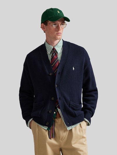 Męski model nosi Regular Fit Strickjacke aus reiner Baumwolle od Polo Ralph Lauren, granatowa, krój regular fit, z przodu logo, dzianina, guziki, kieszenie, długi rękaw, widok całej sylwetki z przodu.