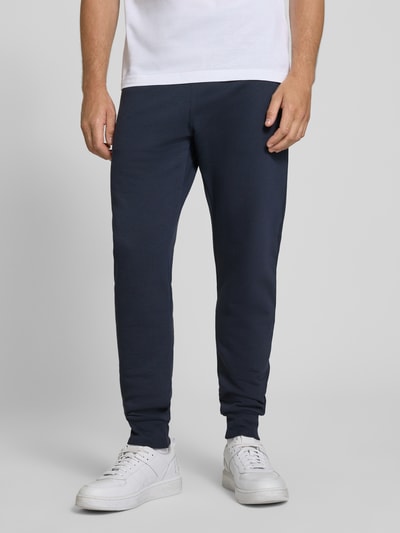Männermodel trägt Slim Fit Sweatpants aus reiner Baumwolle von Paul Smith in Dunkelblau, sichtbarer Elastikbund, Nahaufnahme Unterkörper. Herren Sweatpants mit seitlichen Eingrifftaschen, Gesäßtaschen, Innenbeinlänge bei Größe M 43 cm.
