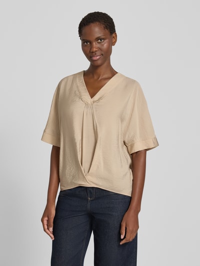 Frauenmodel trägt Blusenshirt mit V-Ausschnitt von Christian Berg Woman in Beige, lockere Form, halbarm, dezente Drapierung, Ganzkörperansicht von vorne.