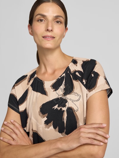 Frauenmodel trägt Regular Fit Kurzarmbluse aus Viskose-Mix Modell 'NOS JULI' von Betty Barclay, Beige mit schwarzem Muster, Nahaufnahme Oberkörper, Damen Kurzarmbluse von Betty Barclay.