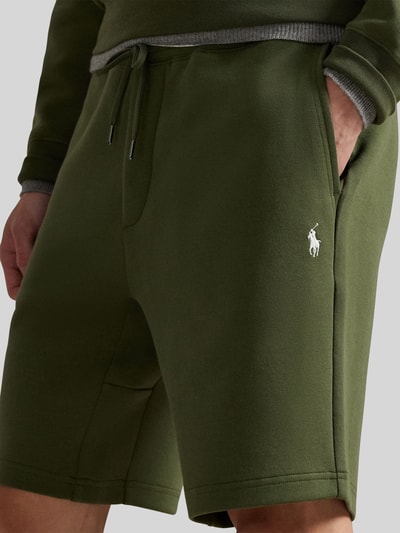 Männermodel trägt Regular Fit Sweatshorts aus Baumwoll-Mix von Polo Ralph Lauren, unifarbenes Olivgrün, Logo-Stitching, Nahaufnahme Oberschenkel.