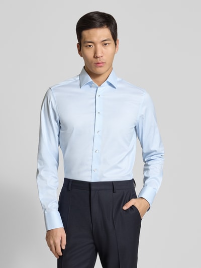 Męski model nosi Slim Fit Business-Hemd mit Kentkragen von ETERNA, jasnoniebieski, czysta bawełna, długi rękaw, sportowe mankiety, listwa guzikowa, długość tyłu w rozmiarze 40: 80 cm, szerokość ramion w rozmiarze 40: 45 cm, długość rękawów w rozmiarze 40: 66 cm, całkowity widok z przodu.