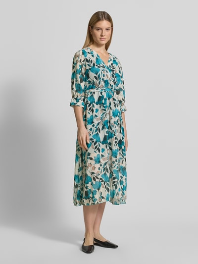Frauenmodel trägt Midikleid in Wickel-Optik Modell 'Mo44moo' von ZABAIONE aus Chiffon mit Allover-Look, V-Ausschnitt und Bindegürtel, Ganzkörperansicht von vorne.