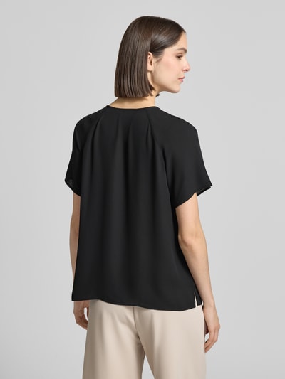 Frauenmodel trägt Blusenshirt mit Schmetterlingsärmeln und Schlüsselloch-Ausschnitt von Comma, schwarze Loose-Fit-Bluse mit Raffungen, Rückenlänge 66 cm, Ärmellänge 16 cm, Ganzkörperansicht Rückansicht.