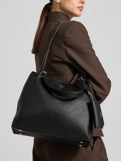 Vrouwenmodel draagt Handtasche in Leder-Optik Model 'LORALLA' van GUESS in zwart met Logodetail, getailleerd hoofdvak met overslag, smalle schouderband, breedte 30 cm, lengte 30 cm, diepte 10 cm, schouderbandlengte 76 cm, detailopname rechterzijde