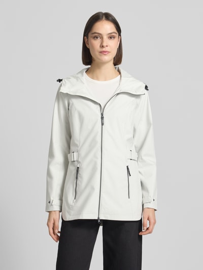 Vrouwenmodel draagt Regular Fit Regenmantel met logodetail van G.I.G.A. DX, lichtgrijs met capuchon, tweewegritssluiting, steekzakken, ruglengte 76 cm, schouderbreedte 40 cm, borstwijdte 50 cm, mouwlengte 66 cm, ganzekörperaanzicht van voren