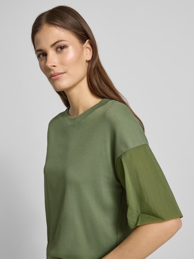 Kobiece model prezentuje T-Shirt mit Rundhalsausschnitt und Tunnelzug od Marc Cain, mieszanka bawełny i elastanu, krój relaxed fit, okrągły dekolt, rękawy z zakładką, długość tyłu w rozmiarze 36: 51 cm, półzbliżenie z przodu.