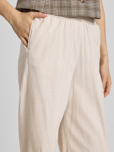 Frauenmodel trägt Wide Fit Stoffhose mit elastischem Bund Modell 'Poppy' von JJXX in Beige, glatte Textur, Eingrifftaschen, Nahaufnahme Oberkörper.