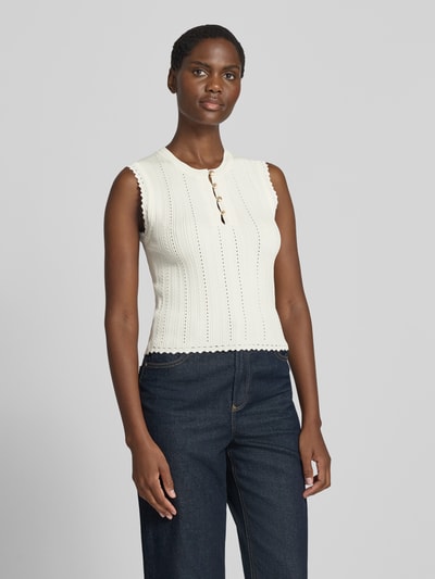 Frauenmodel trägt Stricktop in Pointelle-Strick mit kurzer Knopfleiste von GUESS, cremefarben, Rundhalsausschnitt, Nahaufnahme Oberkörper. Modell 'CARMEN', Viskose-Mix, körpernaher Schnitt, Rückenlänge 49 cm bei Größe S.