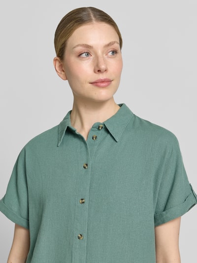 Frauenmodel trägt Relaxed Fit Bluse aus Leinen-Viskose-Mix Modell 'Lava' von FREE/QUENT in hellem Grün, sichtbare Knopfleiste, Nahaufnahme Oberkörper.