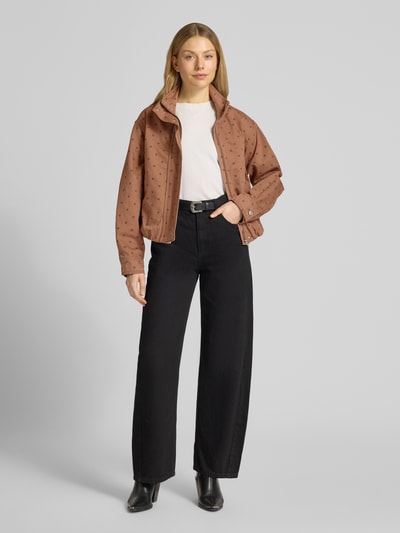 Frauenmodel trägt Jacke mit verdecktem Reißverschluss Modell 'DOTS' von Mango aus reiner Baumwolle, Ganzkörperansicht von vorne.