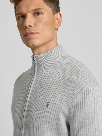 Männermodel trägt Strickjacke mit Reißverschluss von Polo Ralph Lauren, Reine Baumwolle, Regular-Fit, Gerippte-Abschlüsse, Stehkragen, Label-Stitching, Eingrifftaschen, Farbton Hellgrau, Nahaufnahme Oberkörper.