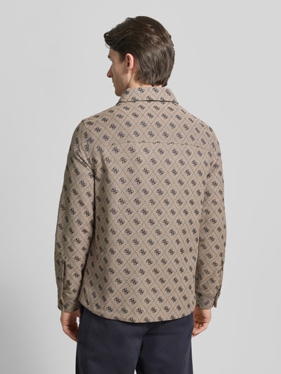 Männermodel trägt Regular Fit Jacke mit Brusttasche von Guess, beige mit Allover-Logo-Stitching, Baumwoll-Mix, Ganzkörperansicht Rückansicht. Rückenlänge bei Größe M: 73 cm, Schulterbreite: 45 cm, Brustweite: 51 cm, Ärmellänge: 65 cm, Umlegekragen, Reißverschluss, Eingrifftaschen.