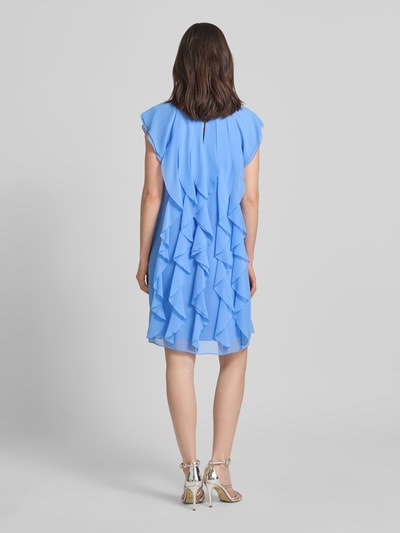 Modelka prezentuje Relaxed Fit Minikleid mit Allover-Rüschenbesatz od Vera Mont, niebieski materiał, okrągły dekolt, kryta halka, rękaw typu kappa, długość tyłu w rozmiarze 36: 90 cm, szerokość w rozmiarze 36: 39 cm, widok całej sylwetki z tyłu.