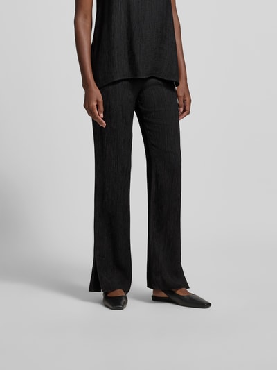 Frauenmodel trägt Straight Fit Stoffhose aus Viskose-Mix von Anine Bing mit Strukturmuster, elastischem Bund und Eingrifftaschen, Nahaufnahme Unterkörper.