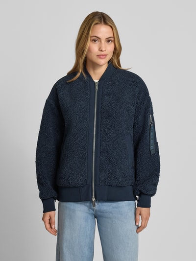Frauenmodel trägt Teddyjacke mit Stehkragen Modell 'Emeline' von MOS MOSH in Dunkelblau, lockere Passform, Reißverschlusstasche am Ärmel, Zweiwege-Reißverschluss, seitliche Eingrifftaschen, elastische Abschlüsse, dezentes Label-Detail, strukturierte Oberfläche, Ganzkörperansicht von vorne.