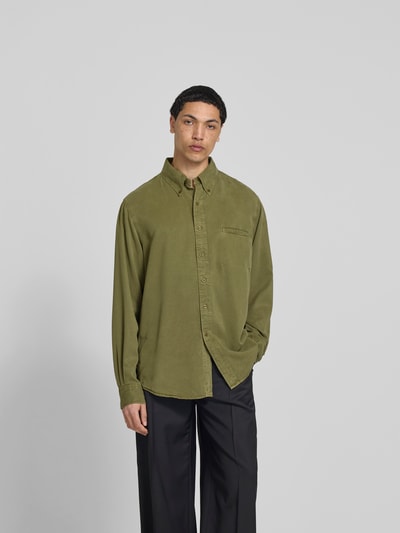 Männermodel trägt Freizeithemd aus reinem Lyocell von Filippa K in Olivgrün mit Brusttasche, Button-Down-Kragen, Relaxed-Fit, Langärmelig, Ganzkörperansicht von vorne.
