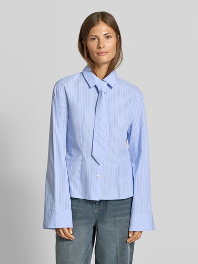 Frauenmodel trägt Hemdbluse aus reiner Baumwolle mit integrierter Krawatte von MYON, feine blaue Streifen, taillierte Passform, Nahaufnahme Oberkörper.