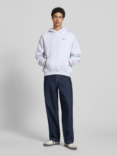 Männermodel trägt Oversized Fit Hoodie mit Logo-Stitching von KARL KANI in hellgrau, Baumwoll-Mix, Känguru-Tasche, Kapuze, Ganzkörperansicht von vorne.