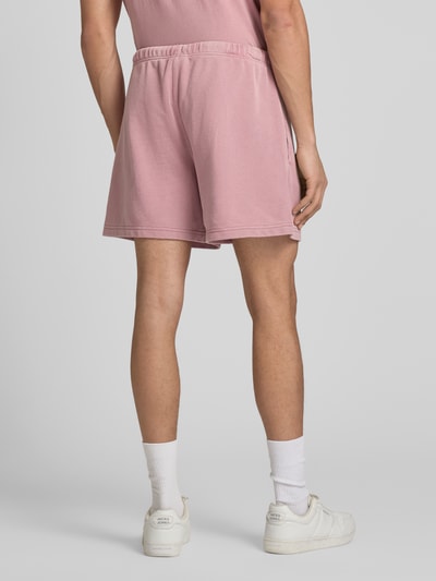 Männermodel trägt Sweatshorts mit Eingrifftaschen von CHAMPION in Rosa, Baumwoll-Mix, Regular Fit, Ganzkörperansicht Rückansicht.