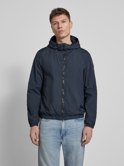 Männermodel trägt Kurtka z kapturem model 'NIGLE' von Peuterey, krój regular fit, zamek błyskawiczny dwustronny, wpuszczane kieszenie, długość tyłu w rozmiarze M 69 cm, szerokość ramion w rozmiarze M 47 cm, szerokość klatki piersiowej w rozmiarze M 56 cm, długość rękawów w rozmiarze M 68 cm, kolor ciemnoniebieski, gładka tekstura. Ganzkörperansicht von vorne.