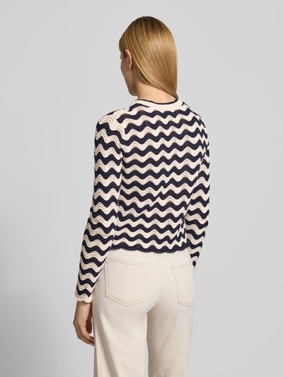Frauenmodel trägt Strickjacke im Allover-Look mit Rundhalsausschnitt von Christian Berg Woman aus Reine Baumwolle, Regular-Fit, Knopfleiste, Farbe Creme-Schwarz, sichtbare Struktur und wellenförmiges Muster, Rückenlänge bei Größe S: 53 cm, Ärmellänge bei Größe S: 66 cm, Ganzkörperansicht Rückansicht.