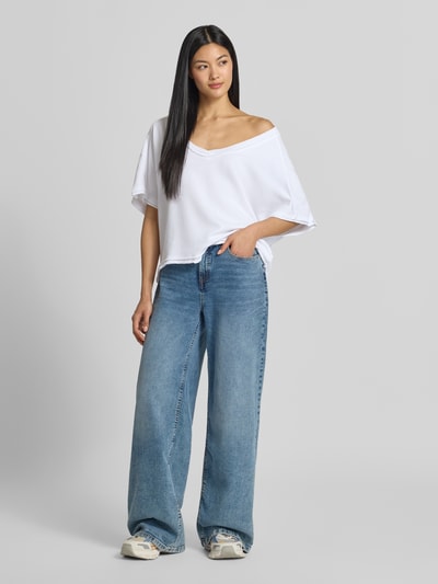 Frauenmodel trägt Sweatshirt mit 1/2-Arm von American Vintage aus reiner Baumwolle in Weiß, gerader Schnitt, tiefer V-Ausschnitt, Ganzkörperansicht von vorne.