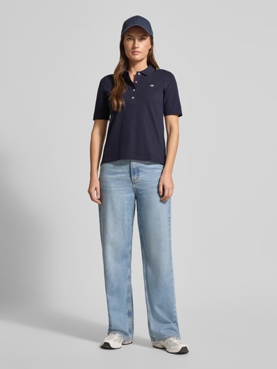 Frauenmodel trägt Poloshirt aus Baumwolle mit Label-Detail von GANT in Dunkelblau, Gerader Schnitt, Polokragen, 1/2-Arm, Ganzkörperansicht von vorne.