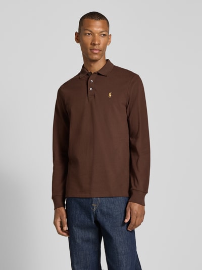Männermodel trägt Slim Fit Pullover aus Baumwoll-Mix von Polo Ralph Lauren in Dunkelbraun, kombiniert mit blauer Jeans, Ganzkörperansicht von vorne.
