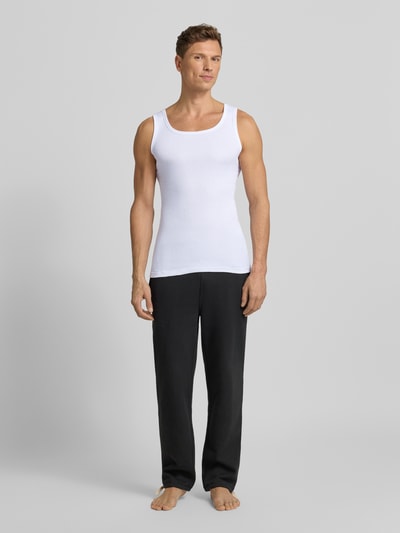 Männermodel trägt Tanktop aus reiner Baumwolle im 2er-Pack von TOM TAILOR mit feiner Rippenstruktur, schmaler Schnitt, Rundhalsausschnitt, weiße Farbe, Ganzkörperansicht von vorne.