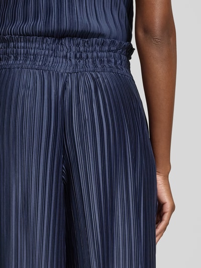 Frauenmodel trägt GUIDO MARIA KRETSCHMER WOMAN Wide Fit Hose mit elastischem Bund Modell 'Mala', dunkelblaues Strukturmuster, Kordelzug, Nahaufnahme Oberkörper seitlich