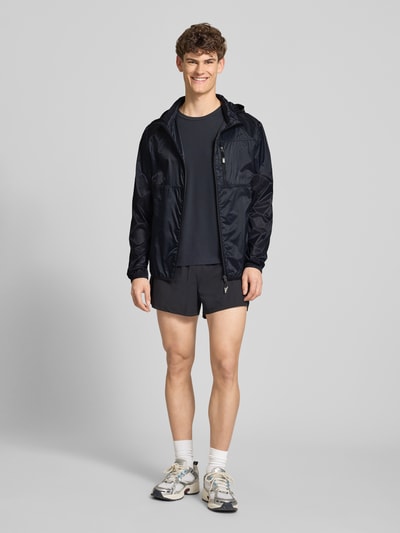Männermodel trägt Regular Fit Jacke mit Stehkragen Modell 'Berg' von Ellesse in Dunkelblau, glatte Textur, Ganzkörperansicht von vorne, Napoleontasche, Reißverschlusstaschen, elastische Abschlüsse, sportlicher Look