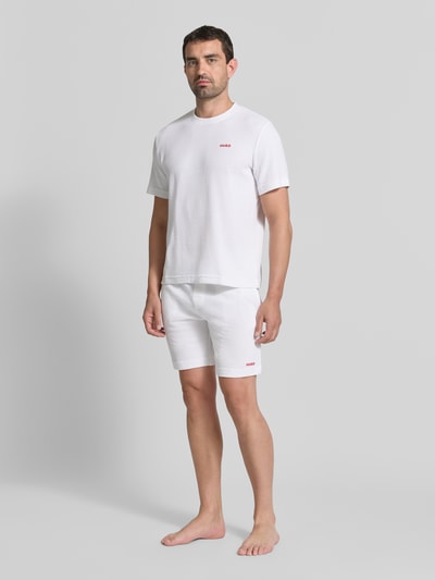 Męskimodel nosi Męski t-shirt z mieszanki bawełny model 'AUSTIN' od HUGO w kolorze białym z subtelną fakturą, całopostaciowy widok z przodu.