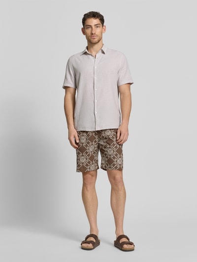 Männermodel trägt Shorts aus Leinen-Mix mit elastischem Bund und Kordelzug von MCNEAL, Relaxed-Fit, braunes Muster, Ganzkörperansicht von vorne. Herren Shorts aus Leinen-Baumwoll-Anteil mit seitlichen Eingrifftaschen und Gesäßtasche, Bundweite 40 cm, Innenbeinlänge 23 cm, Größe M.
