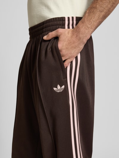 Männermodel trägt Straight Fit Sweatpants mit Logo-Stitching Modell 'Firebird' von adidas Originals aus Baumwoll-Mix, Detailaufnahme.