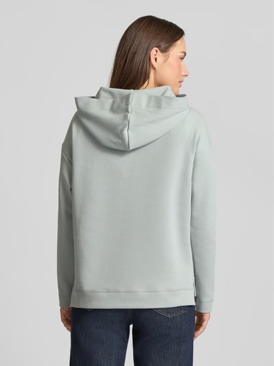 Vrouwenmodel draagt Regular Fit Hoodie met Logo-Applikation van JOOP! in lichtgrijs, katoenmix met capuchon, verlengde achterkant. Ganzkörperansicht Rückansicht.