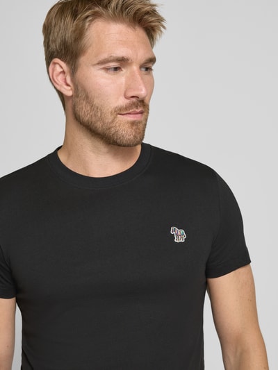 Männermodel trägt Regular Fit T-Shirt aus reiner Baumwolle von Paul Smith in Schwarz mit Label-Stitching, Nahaufnahme Oberkörper. Rückenlänge bei Größe M: 69 cm.