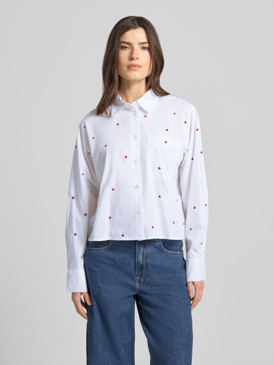 Frauenmodel trägt Boxy Fit Hemdbluse aus reiner Baumwolle von Tom Tailor Denim, Weiß mit roten Herzstickereien, Ganzkörperansicht von vorne.
